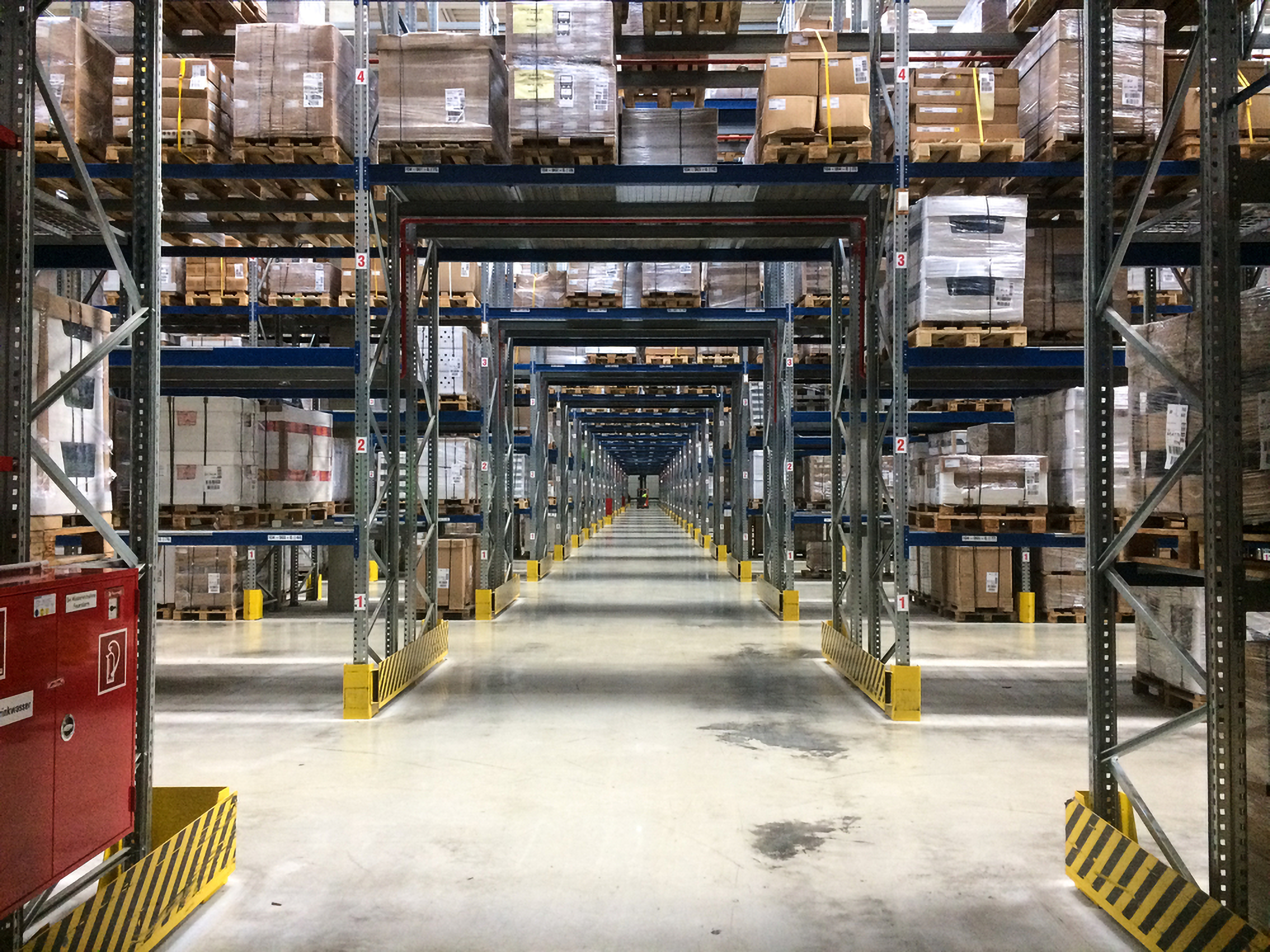 Warehouse interior with tall shelves stacked with pallets and boxes  